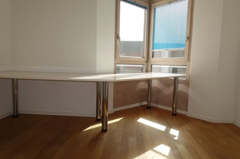 empty room with a desk, wooden floor, white walls, two windows with blinds