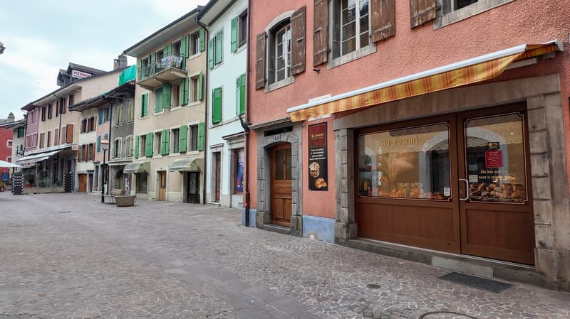Old town street, multiple storefronts, cobblestone roads, some stores have awnings