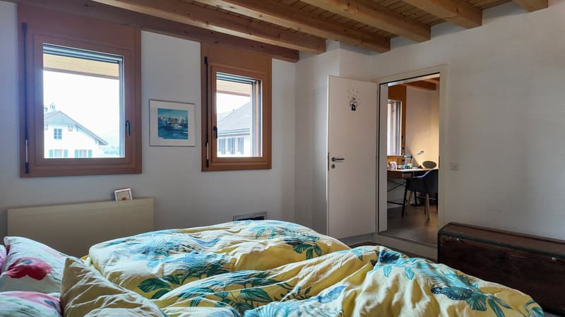 a room with two beds, a wooden ceiling, windows with view, desk, picture frame