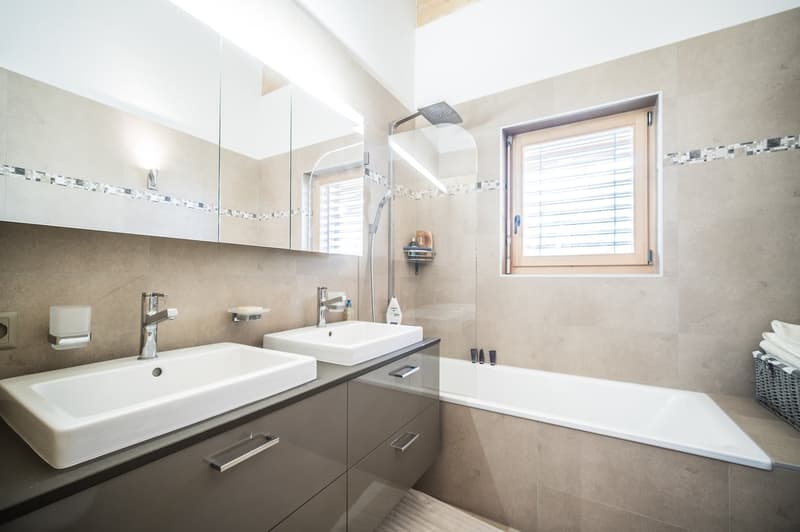 Bathroom with two sinks, shower, bathtub, wall-mounted mirror, and window