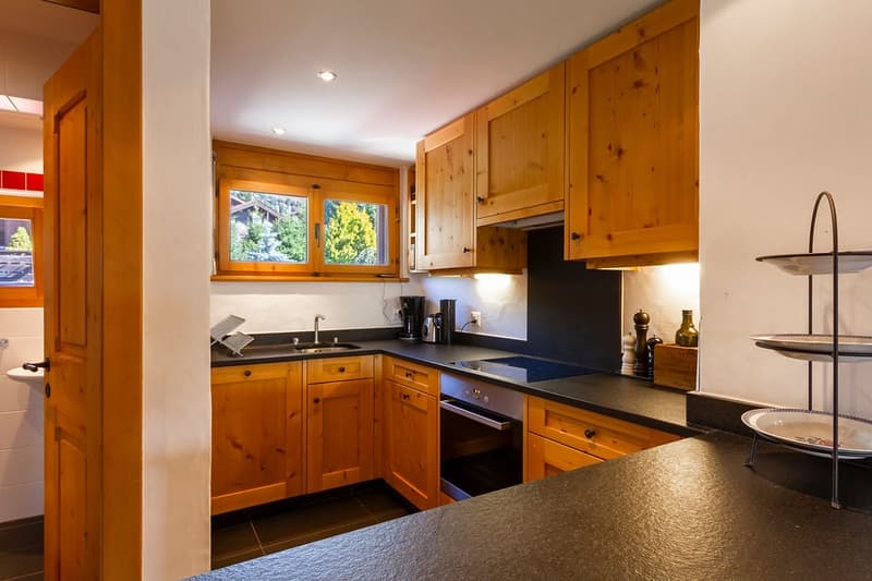 modern kitchen with wooden cabinets, black countertops, island, stainless steel appliances, granite flooring