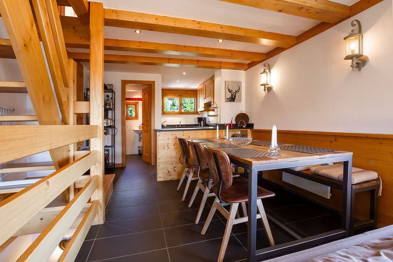 Dining area with dining table, wooden benches, wooden staircase, wooden kitchen counter, lamps, cabinets, deer head painting