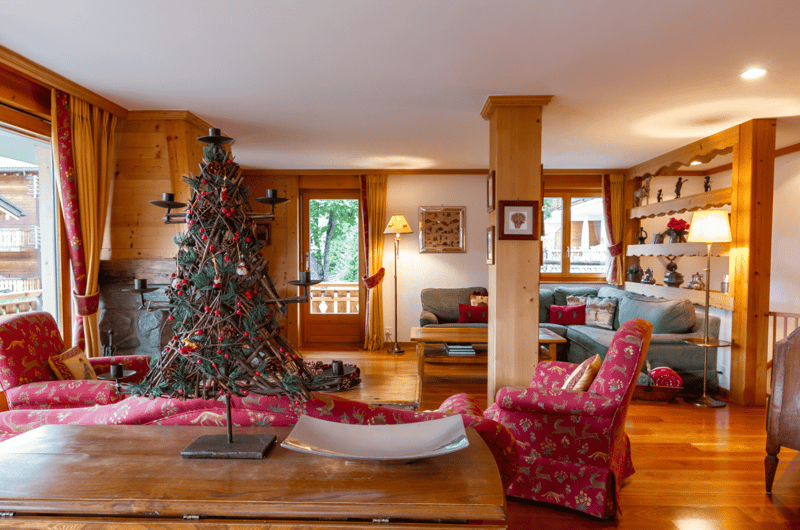 hardwood floor, wooden walls, large windows, Christmas tree, fireplace, armchairs, coffee table, sofa, lamps, shelf, table, picture frame