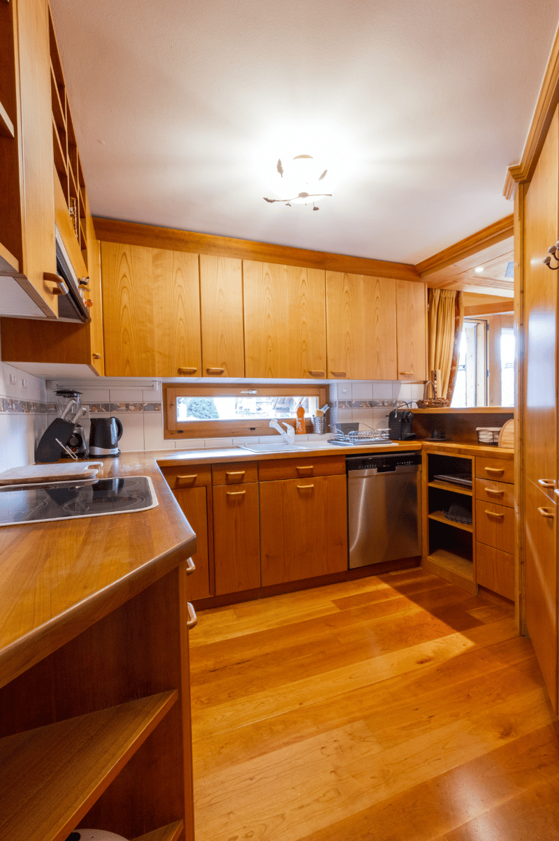 large kitchen, wooden cabinets, granite countertops, modern appliances, double oven, island with stovetop, dishwasher, open shelves, window with outside view, tiled backsplash