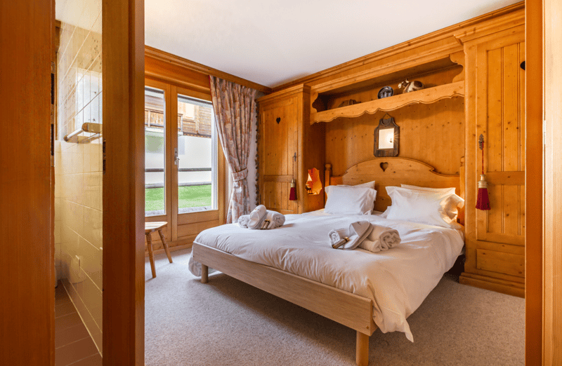 wooden bed, white sheets, wooden bed head, windows, wooden cabinets, wooden chair