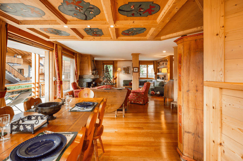 Dining room, wooden flooring, large dining table, fireplace in background, decorated for holidays, two chairs with plaid cushion