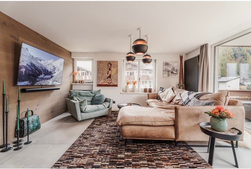 Large sofa, side table, wall mounted TV, rug, large windows, artwork, candle holders with candles