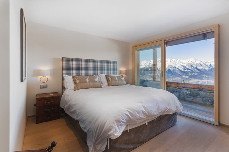 bed, white bedding, wooden nightstand, wall lamps, nightstand drawers, glass sliding doors with terrace, mountain view