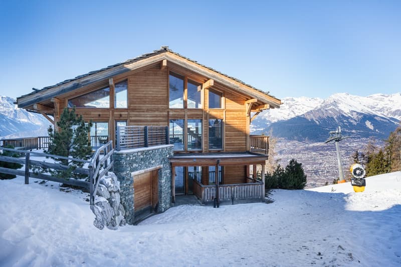 wooden, two stories, balcony, glass windows, elevated entrance, mountains in background