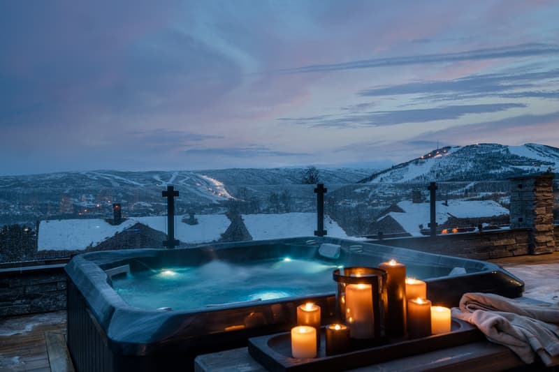 outdoor jacuzzi tub, candle stand, wooden flooring, railings, view of snowy mountains