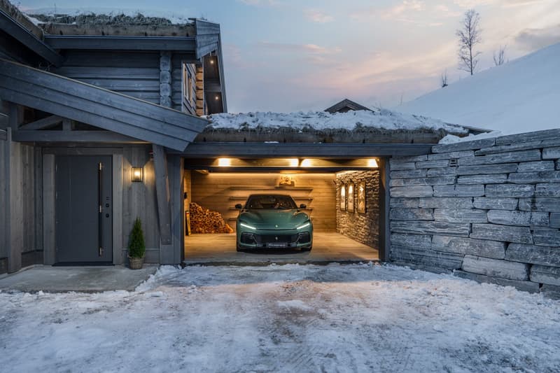 log house, gray garage door, green car parked inside, wooden interior, stone wall