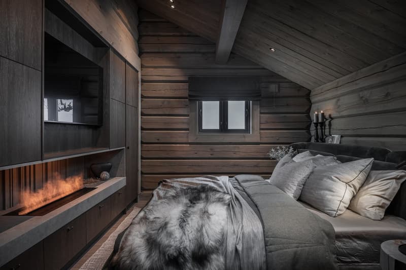 Log cabin, bed, pillows, fireplace, wooden walls, TV, small shelf, lamp
