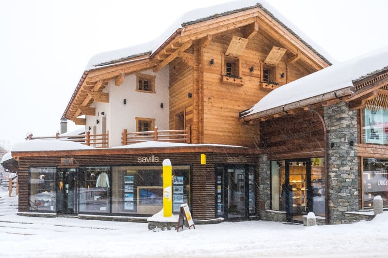 wooden chalet, snow on the roof, glass windows, shops on the ground floor