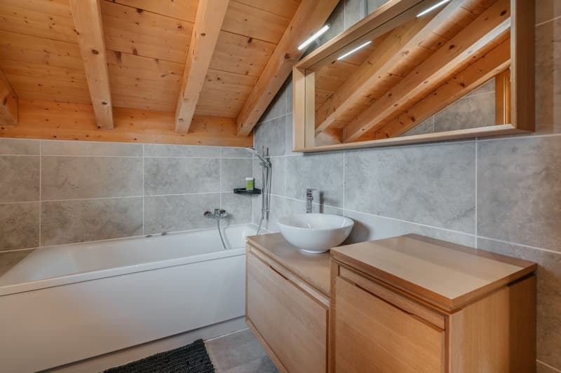 Bathroom with wooden ceiling, bathtub, sink, mirror, wooden cabinet, tiled walls