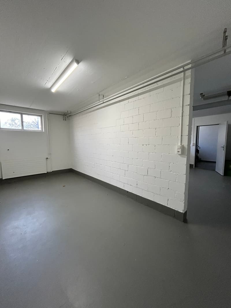 Empty room with white brick wall, gray floor, white ceiling, window, and a door leading to another room
