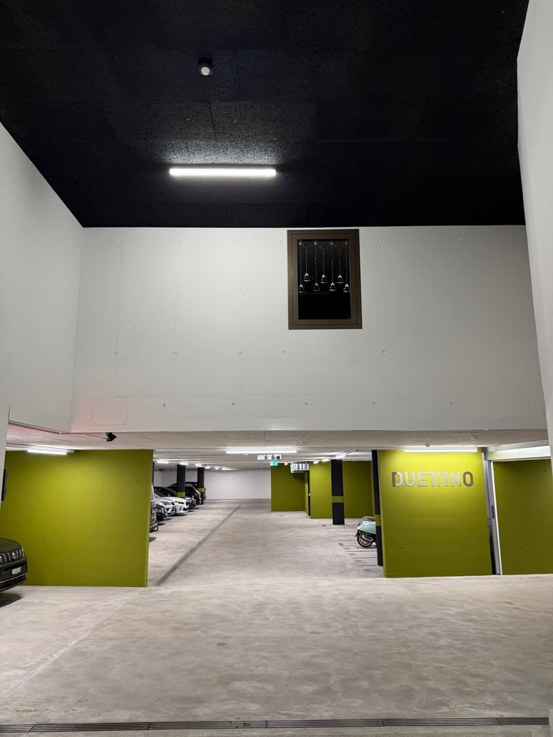 underground parking lot, green walls, white ceiling, cars parked, small window