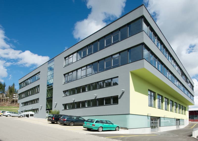 modern office building, gray exterior, glass windows, multiple floors, cars parked in front