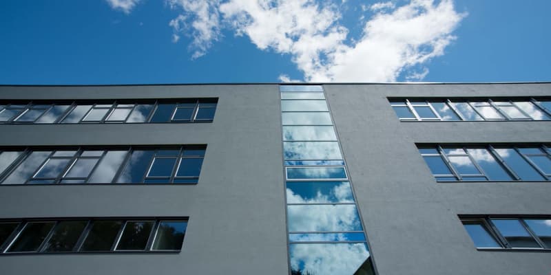 Modern office building with multiple floors, large glass windows, gray exterior, reflective glass panels