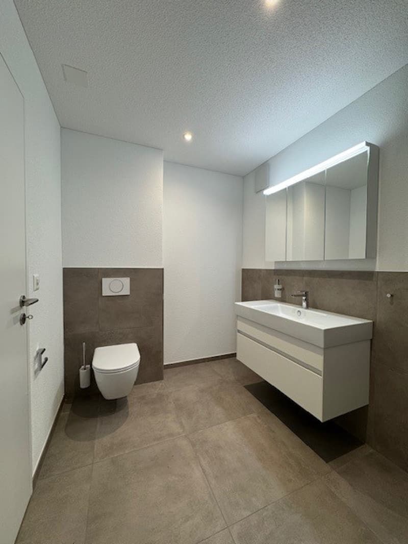 Tiled floor, modern sink, toilet, and mirror with lighting