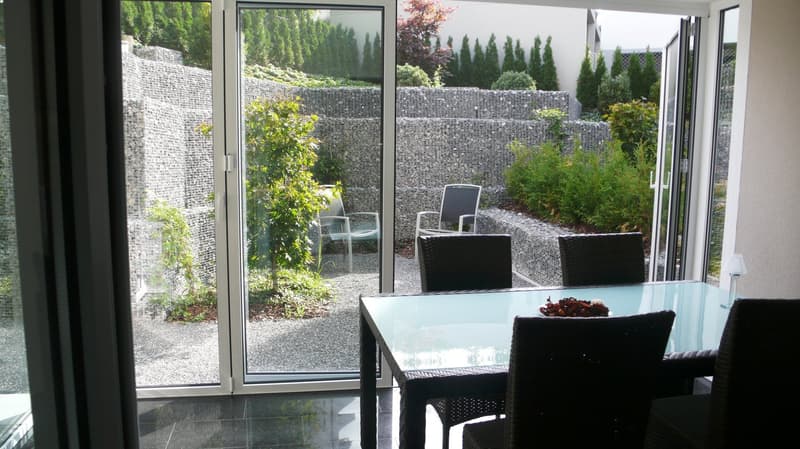 glass doors, large windows, outdoor chairs, dining table, view of the garden