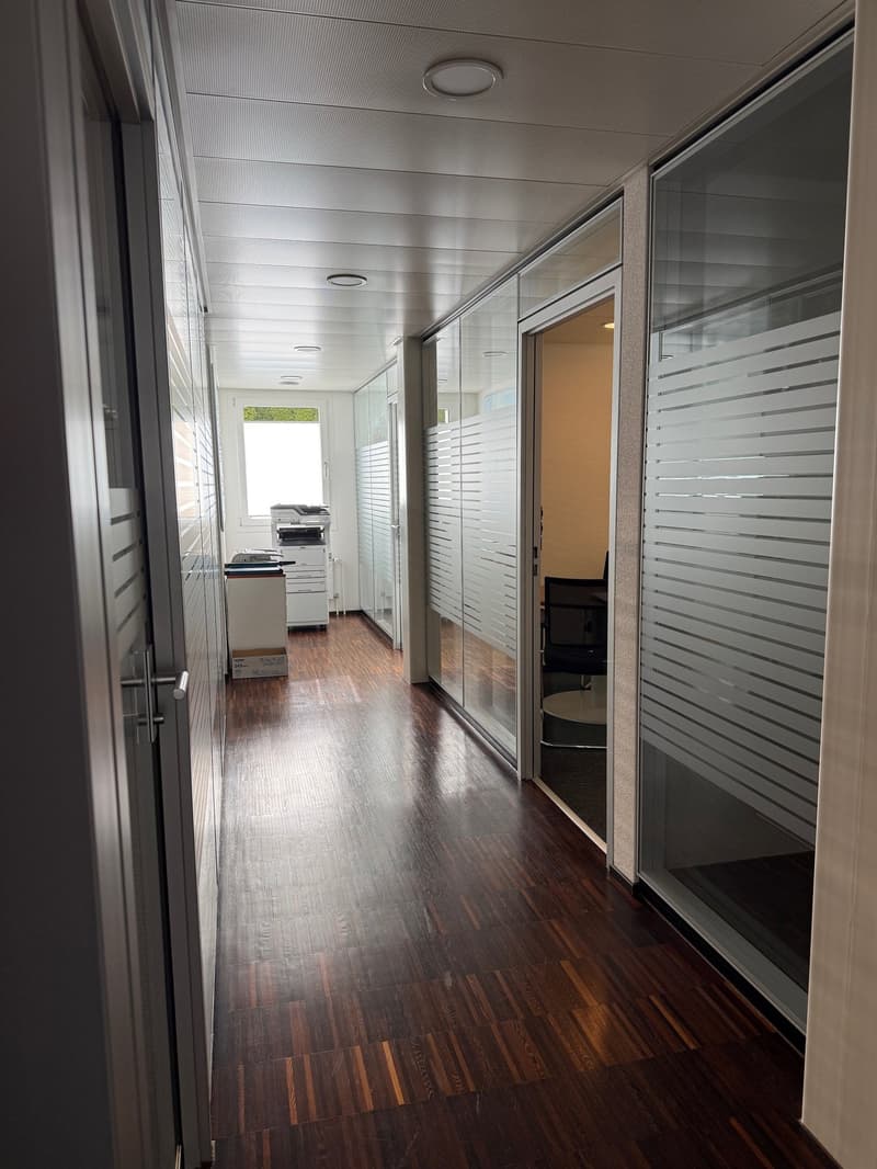 Wooden floor, glass walls, open office space, office equipment, white ceiling