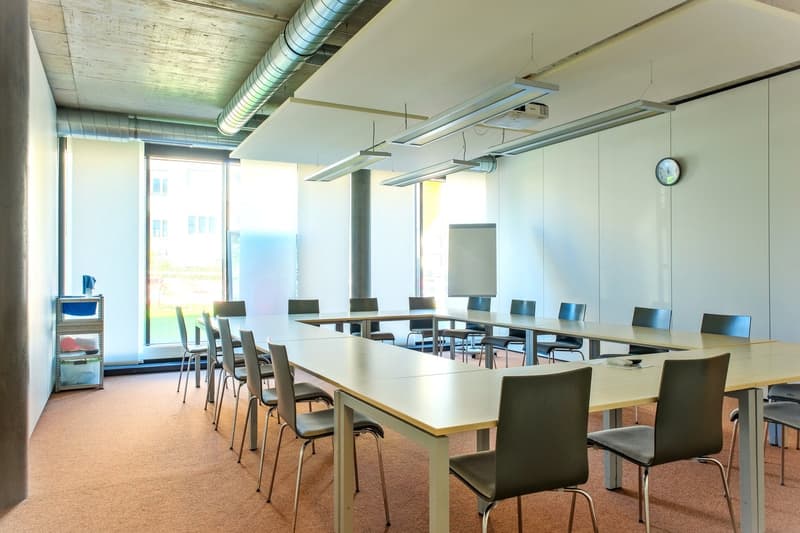 large meeting room with desks, chairs, whiteboard, projector