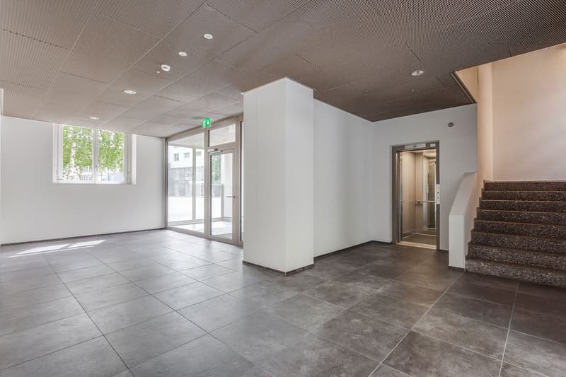 Empty entrance with tiled floor, stairs, elevator, windows with views to outside