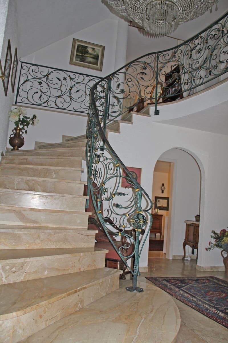 marble staircase, wrought iron railing, chandelier, flower vase, rug
