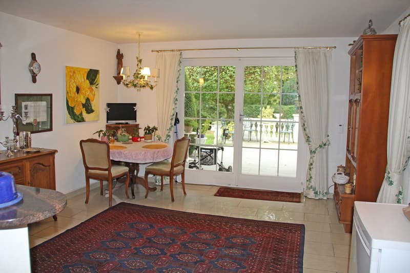 dining room with table, chairs, rug, cabinet, TV, chandelier, curtains, balcony