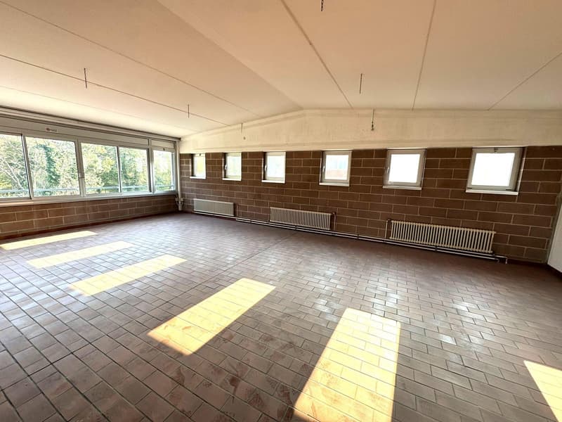 Empty room with large windows, brick walls, wooden tiles, three radiators