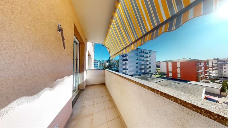 balcony, tiled floor, shaded by awning, view of surrounding buildings