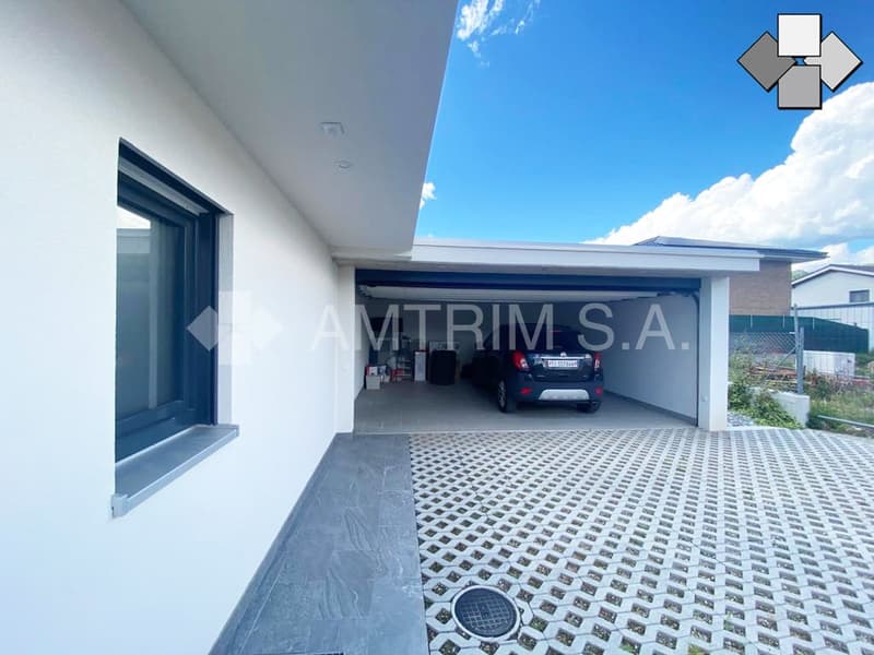 2-story modern house with a garage, paved driveway, and a covered parking area.