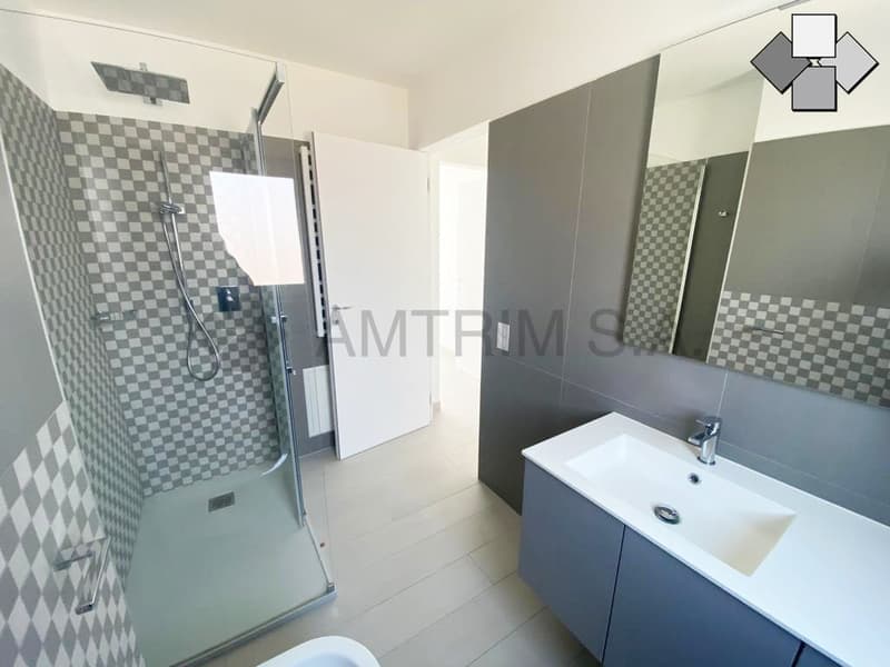 Tiled bathroom with a glass shower enclosure, vanity sink, and mirror cabinet