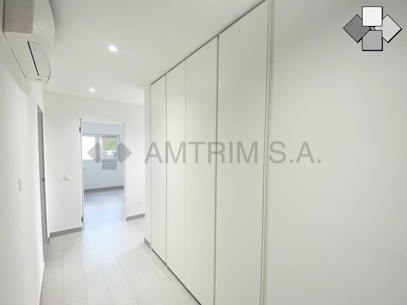 Bright, white hallway with built-in closets and a view of an adjacent room