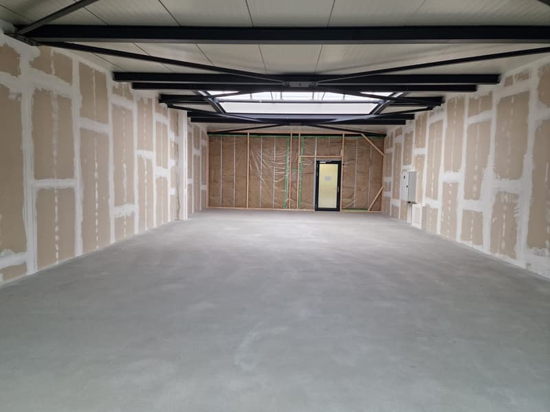 Empty room with concrete floor, unfinished walls, metal beams, glass door, skylight