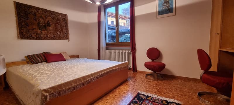 bed, two red chairs, heater, rug, rug, wooden floor