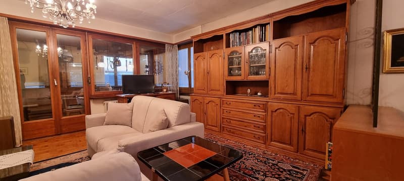Large windows, chandelier, couch, entertainment center, TV, wooden flooring, curtains, rug, wooden furniture