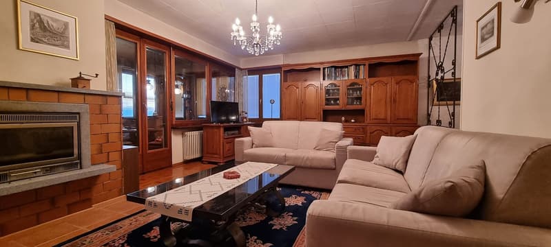 fireplace, large windows, 2 couches, tv, coffee table, chandelier, wooden cabinet, radiator