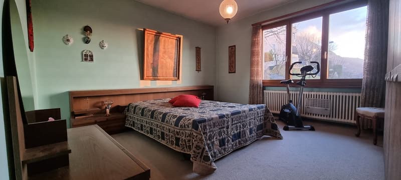 Twin bed, bedside tables, exercise bike, radiator, large window, bedspread