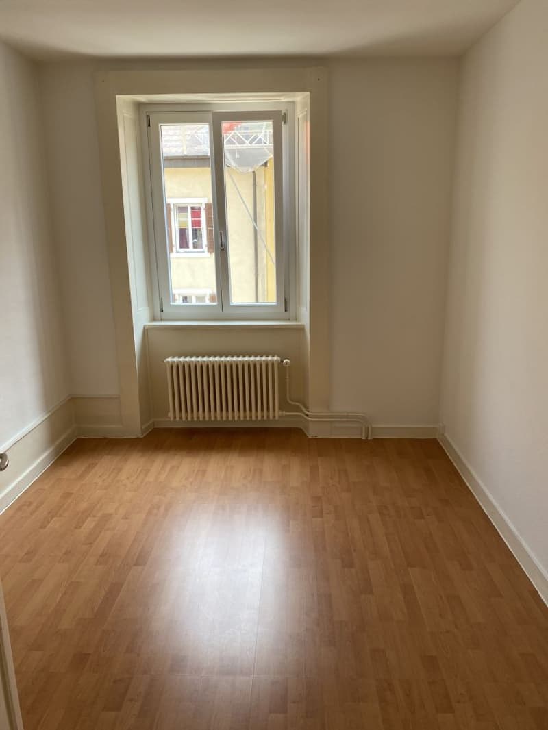 wooden floor, large window, white walls, radiator under window