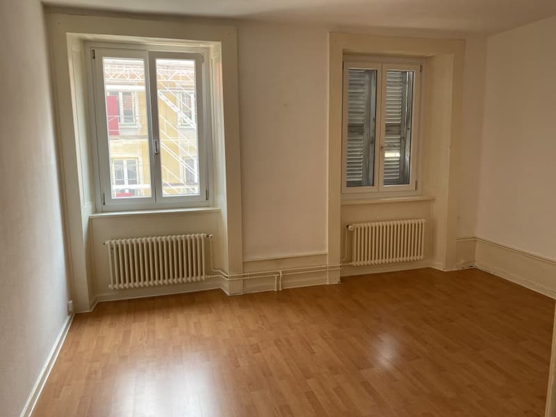 Wooden floor, white walls, two windows, and two radiators. Empty room.