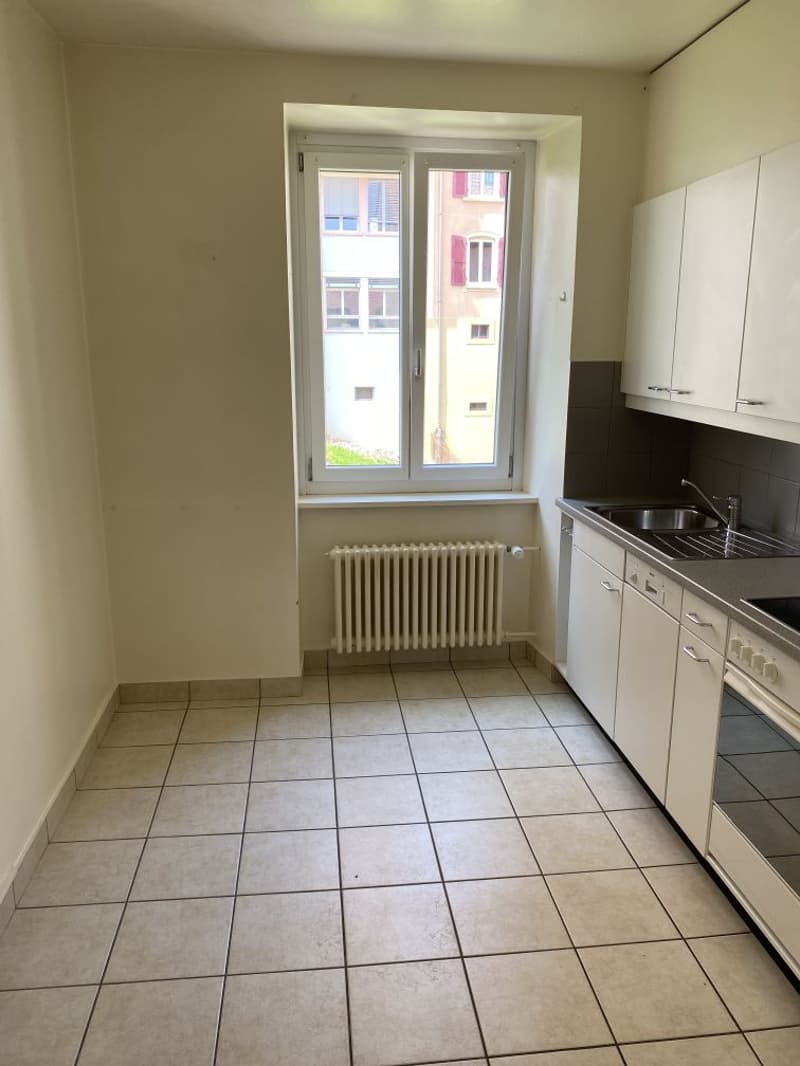 Kitchen: tiled floor, window, radiator, sink, faucet, built-in kitchen cabinets, oven, gas stove