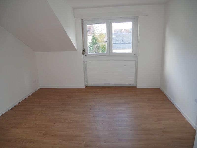 empty room with wooden floor, white walls, large window with blinds, radiator