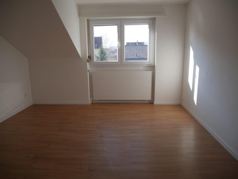 empty room, wooden floor, white walls, single window with white frame, white radiator, ceiling with slope