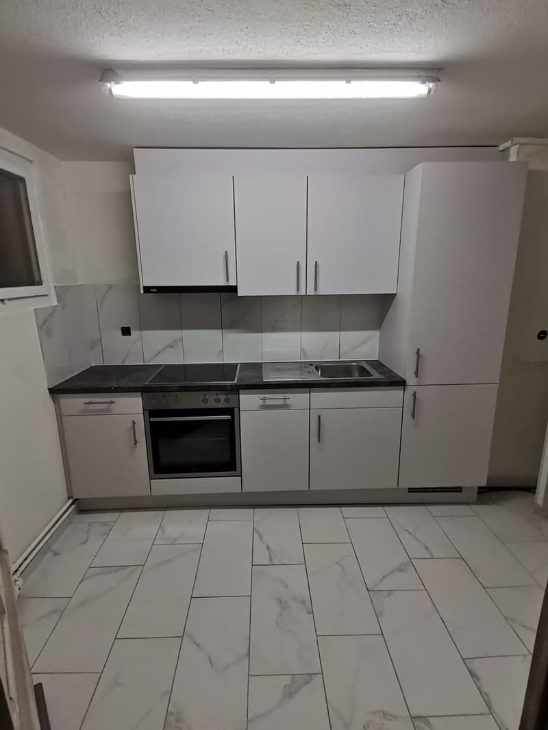 Modern white kitchen, with integrated appliances, marble countertops, and ample cabinetry.