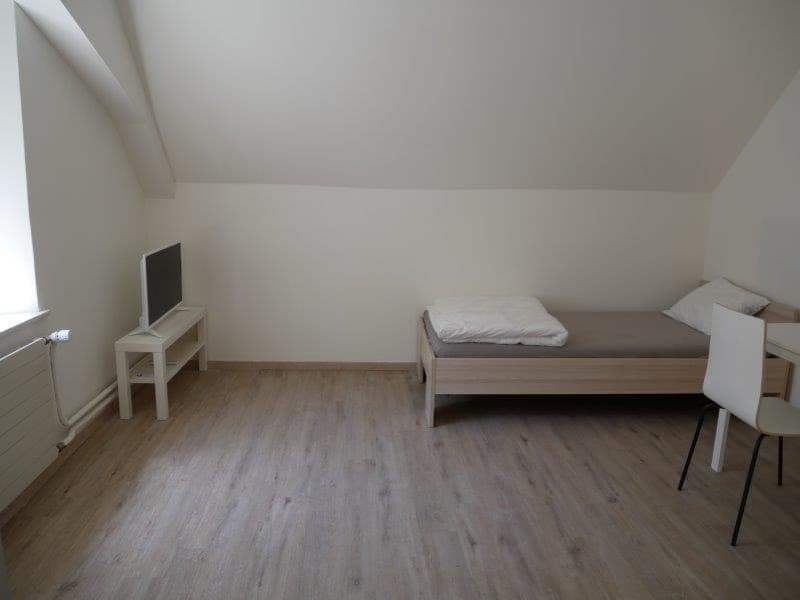 small room with bed, TV, desk, chair, and radiator