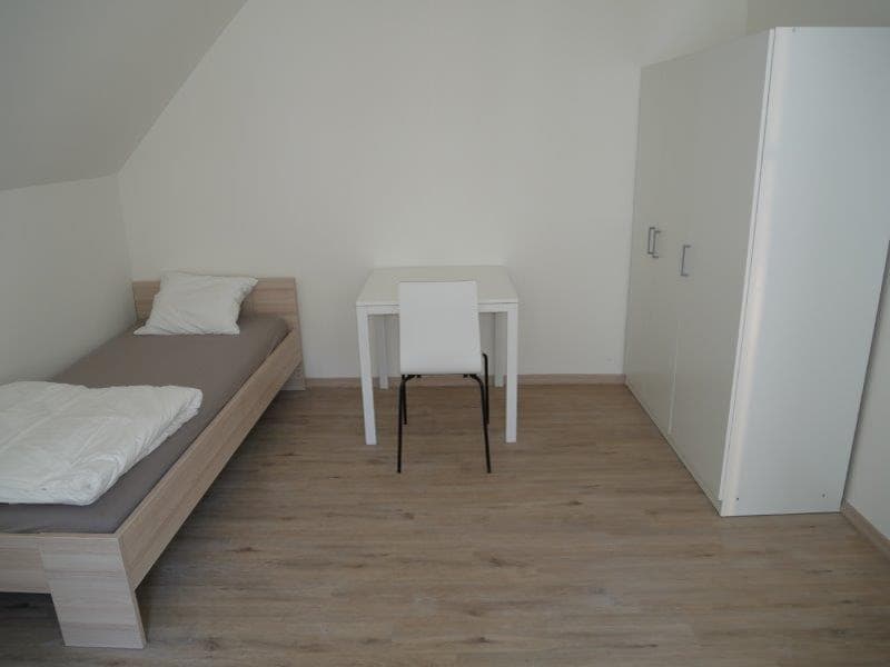 A single bed, a desk with a chair, and a cabinet.