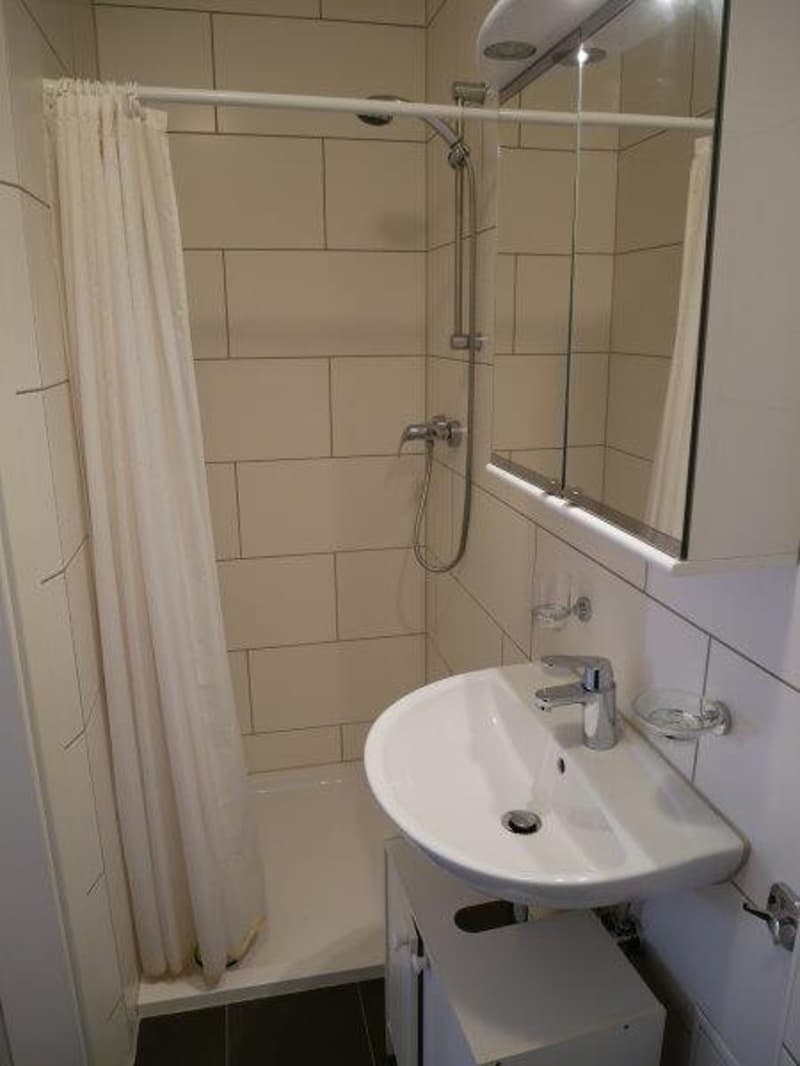 Tiled bathroom with a shower curtain, sink, and mirror