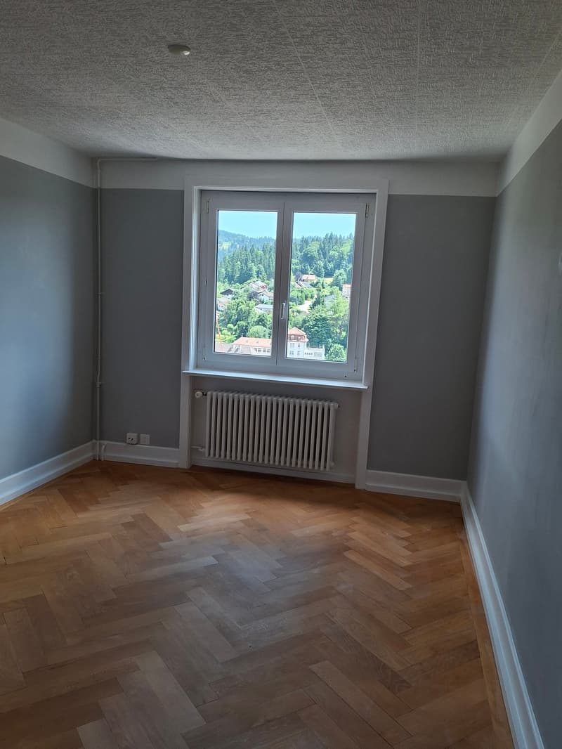 empty room, hardwood floors, white walls, window with view to the forest, radiator