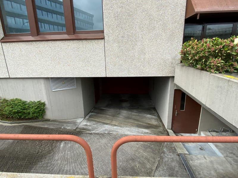 underground garage area with brown door and railings